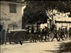 Colonna di soldati con carri e cavalli attraversa un paese